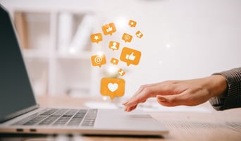 Cropped view of businesswoman typing on laptop at workplace with multimedia icons