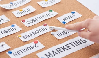 cropped view of woman pointing with pencil on branding inscription on cork board