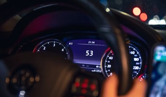 Speed indication and women's hands on the steering wheel in a car at night.