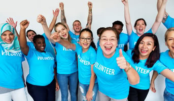 volunteers cheer and support each other while wearing blue volunteer shirts