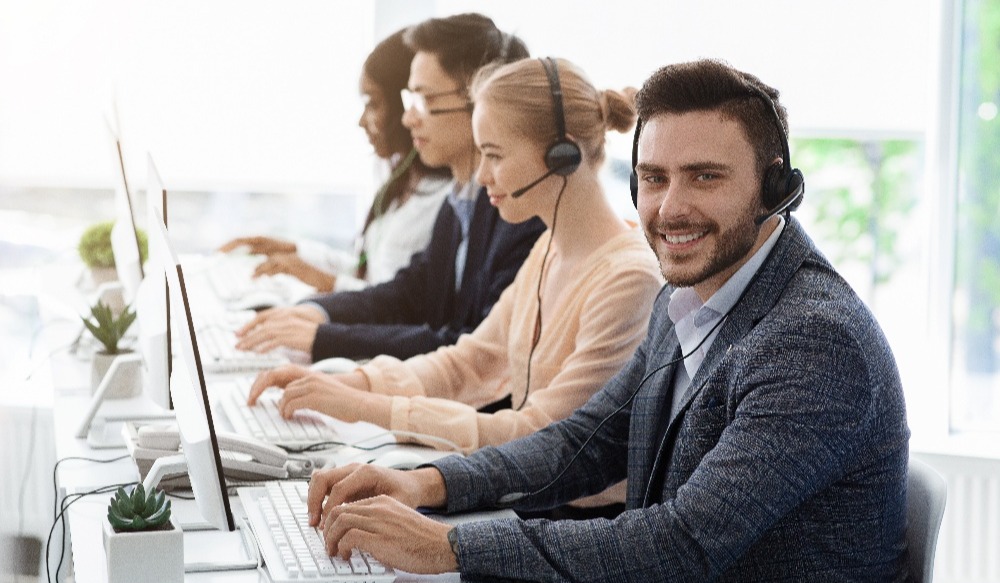 Team of customer service agents with headsets working at computers