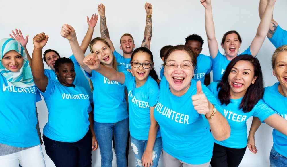 volunteers cheer and support each other while wearing blue volunteer shirts